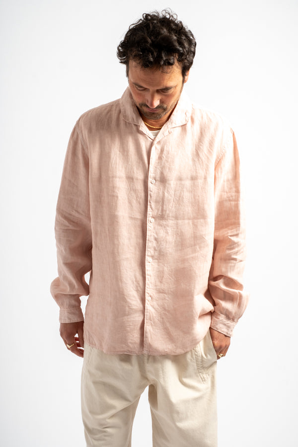 Man wearing a light pink shirt and white pants on a white background