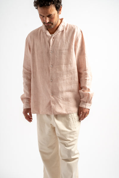 Man wearing a light pink shirt and beige pants on a white background