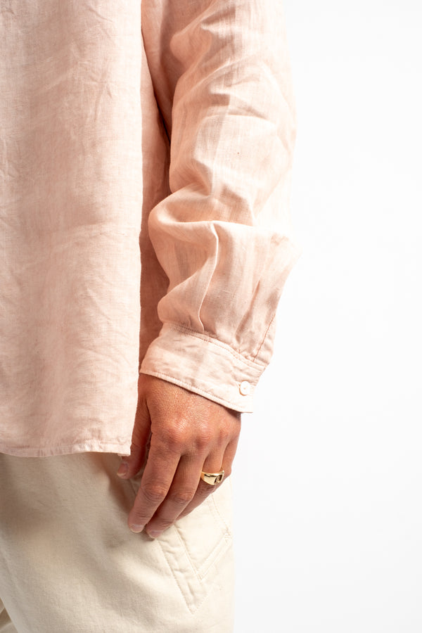 Close-up of a person wearing a light pink shirt and white pants on a white background