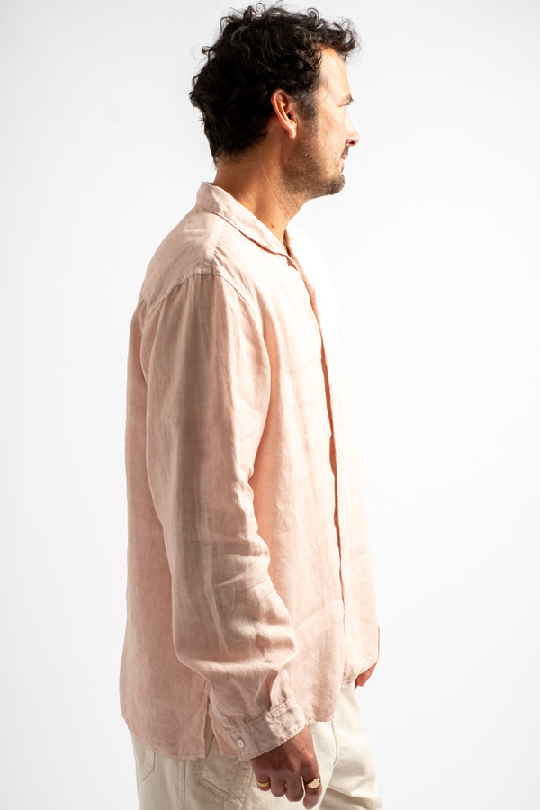 Man wearing a light pink shirt and white pants against a white background