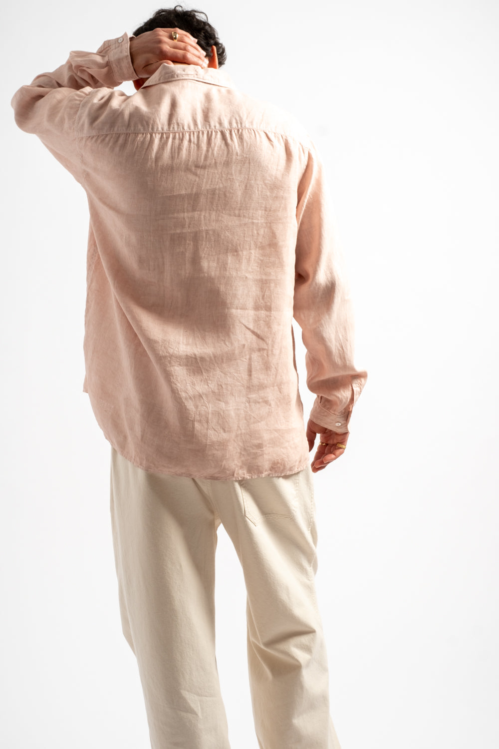 Person wearing a light pink shirt and beige pants on a white background