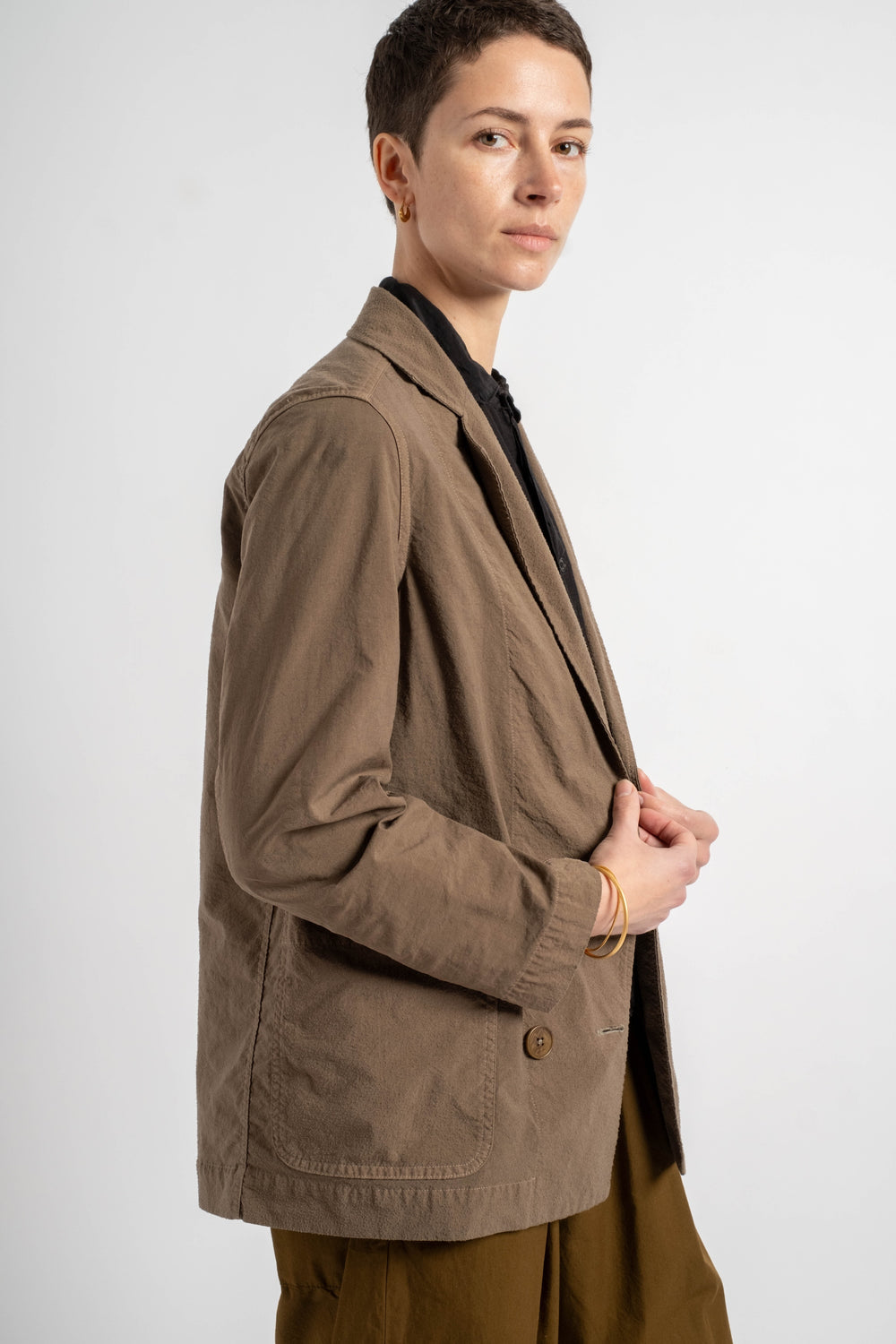 Person wearing a brown blazer on a white background