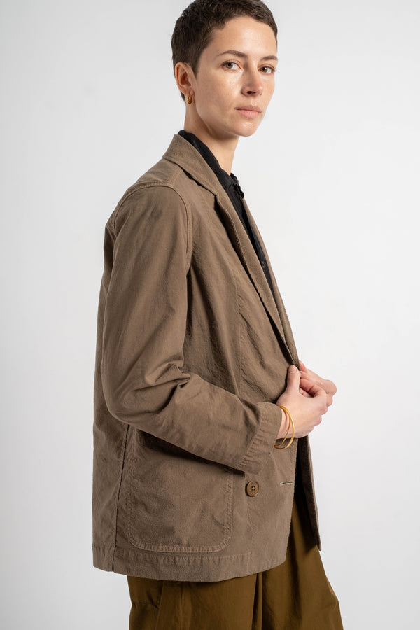 Person wearing a brown blazer on a white background