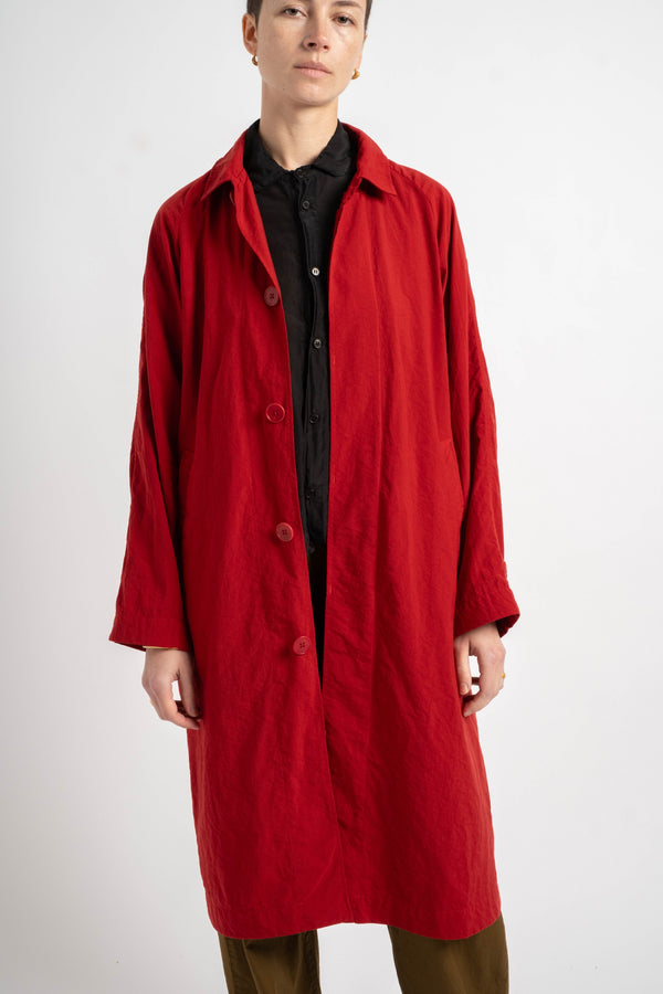 Person wearing a red coat over a black shirt on a white background