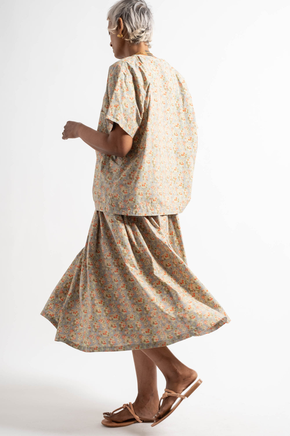 Woman wearing a floral dress and sandals on a white background