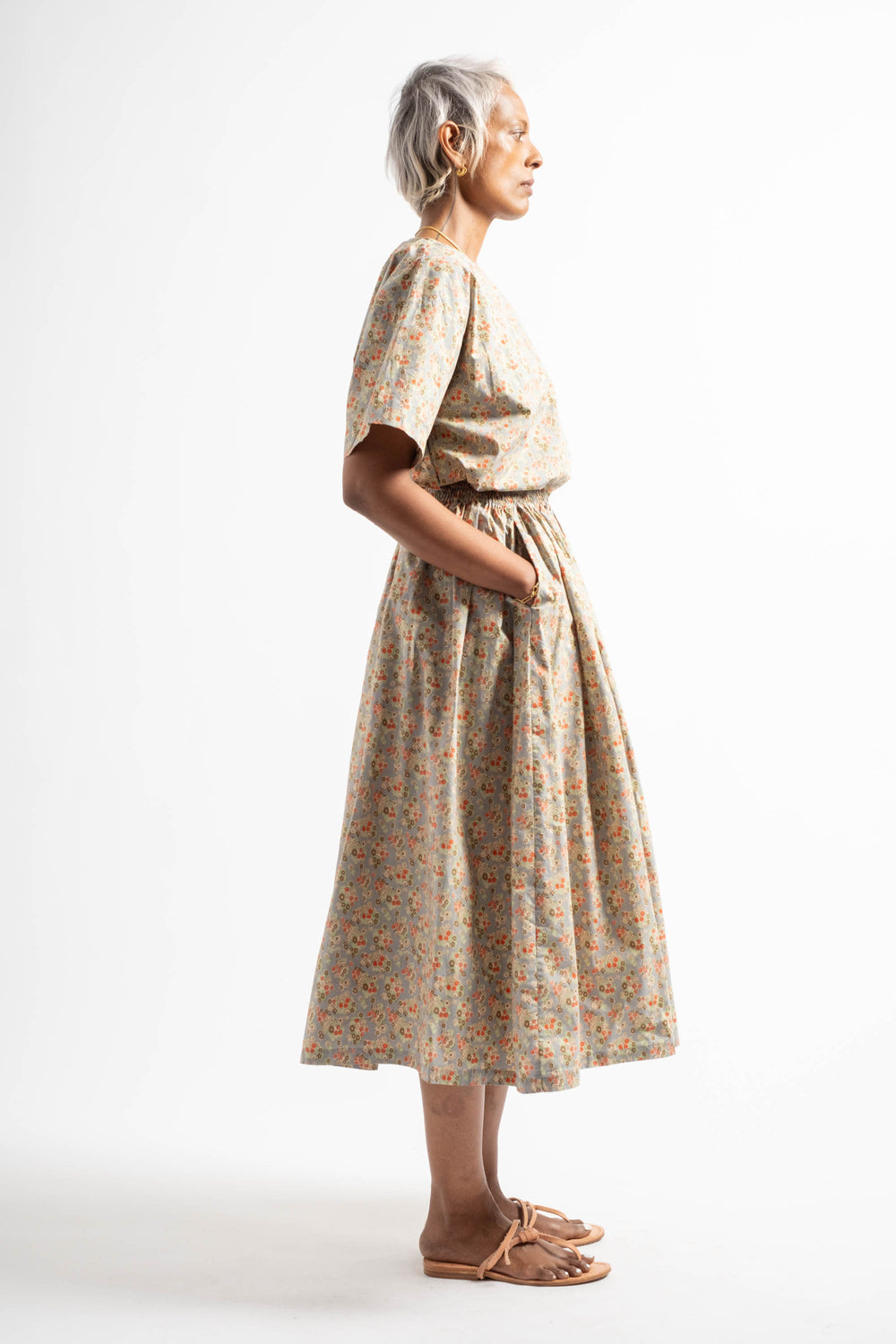 Woman wearing a patterned dress standing against a white background