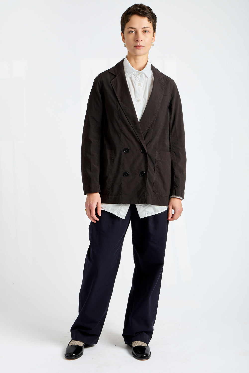 Person wearing a dark blazer over a white shirt with black pants on a white background