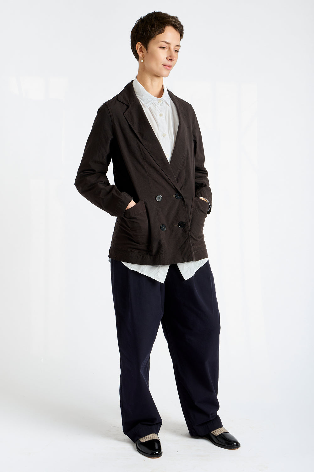 Person wearing a black blazer and dark pants on a white background