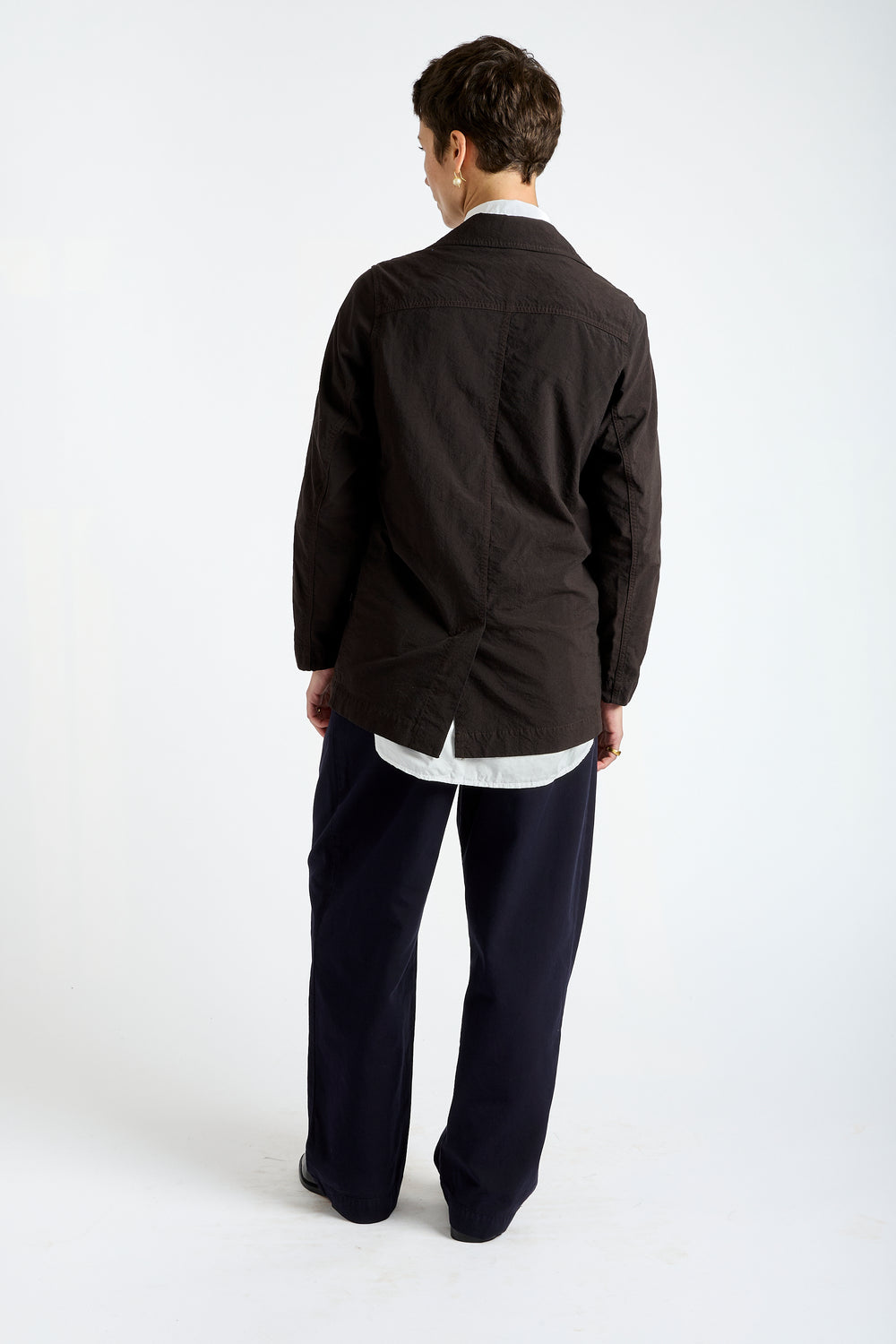 Person wearing a black jacket and dark pants on a white background