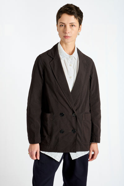 Person wearing a dark brown blazer over a white shirt on a white background